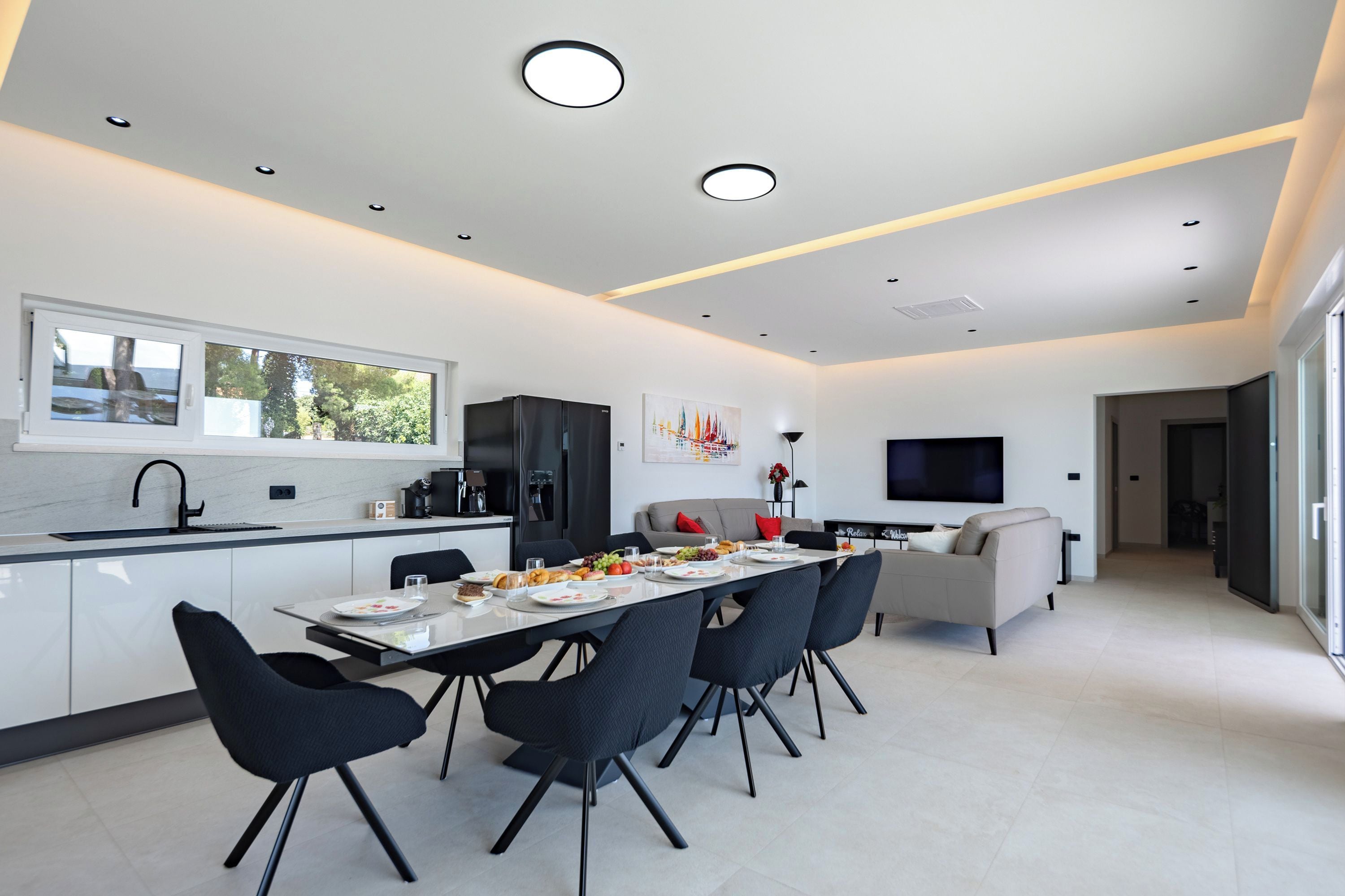 Una cocina moderna con comedor, televisor de pantalla plana y sofá.