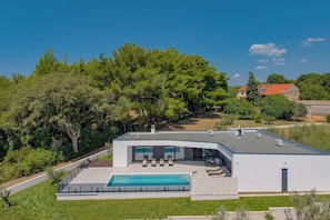 A modern house with a swimming pool, a covered patio, and a view of the surrounding trees. - Villa Peliceti With Grand Pool (Marcana)