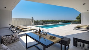 A rooftop terrace with a swimming pool, lounge chairs, and a table set for dining. - Villa Peliceti With Grand Pool (Marcana)