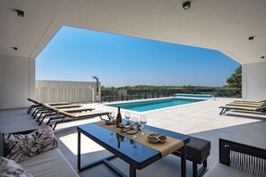 A rooftop terrace with a swimming pool, lounge chairs, and a table set for dining. - Villa Peliceti With Grand Pool (Marcana)