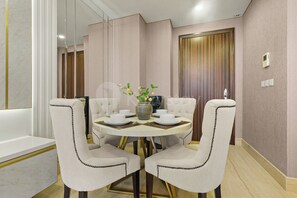 Un coin repas comprenant une table ronde, deux chaises rembourrées, un vase avec des fleurs et un panneau de commande fixé au mur.
