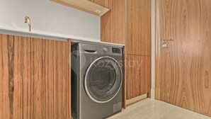 Ein kompakter, moderner Waschraum mit integriertem Wasch- und Trockner, Holzausstattung und einer weißen Arbeitsplatte.
