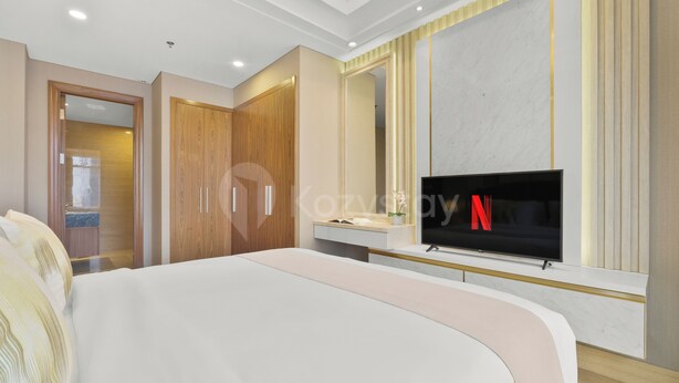 Ein modernes Hotelzimmer mit einem großen Bett, einem an einer Marmorwand montierten Fernseher und einem Holzschrank.