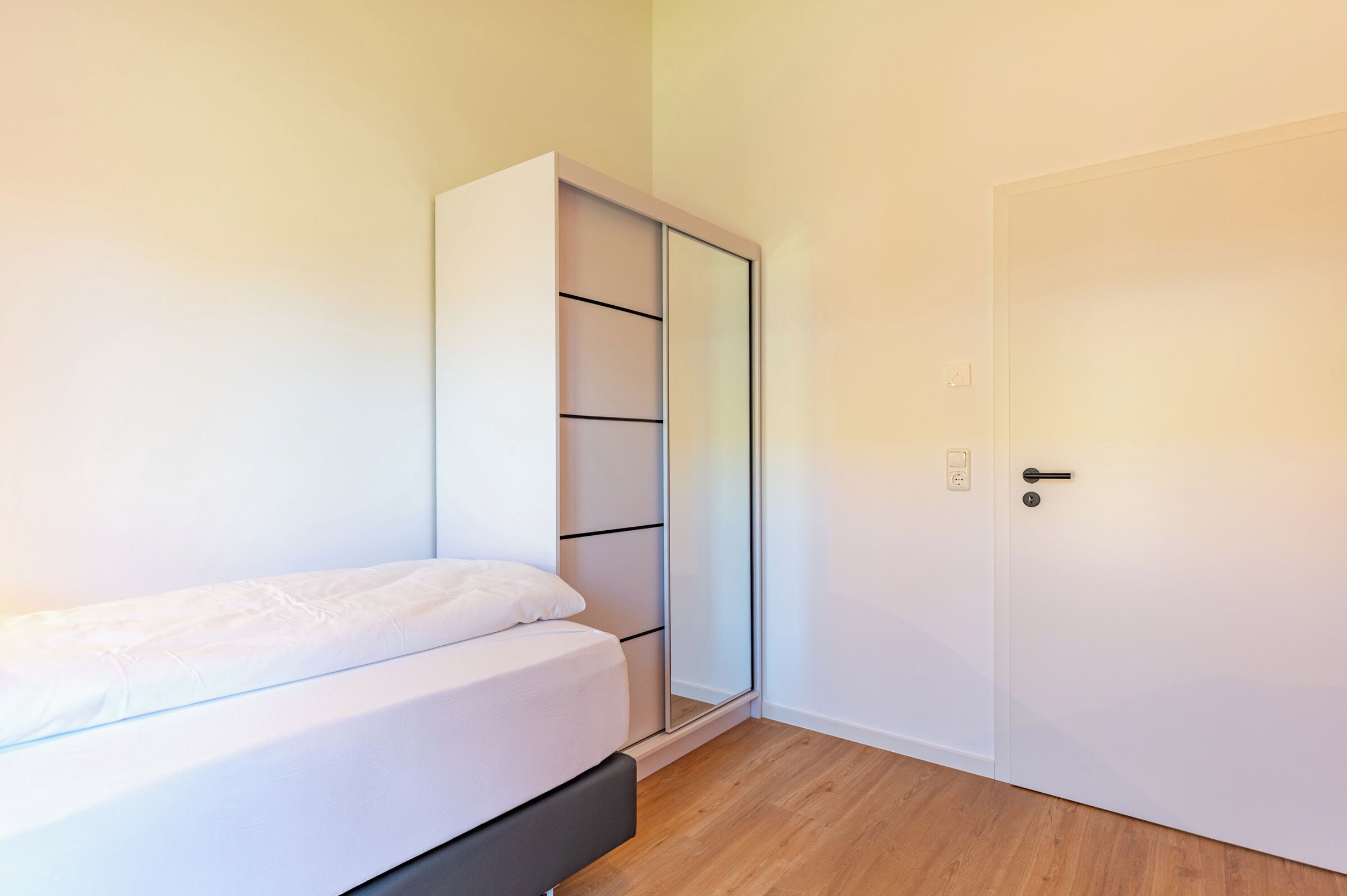 A bedroom with a bed, a wardrobe, and a door.