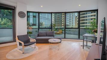 A modern living room with a sofa, armchair, coffee table, and a TV.