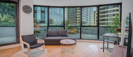 Una sala moderna con sofá, sillón, mesa de centro y televisión.