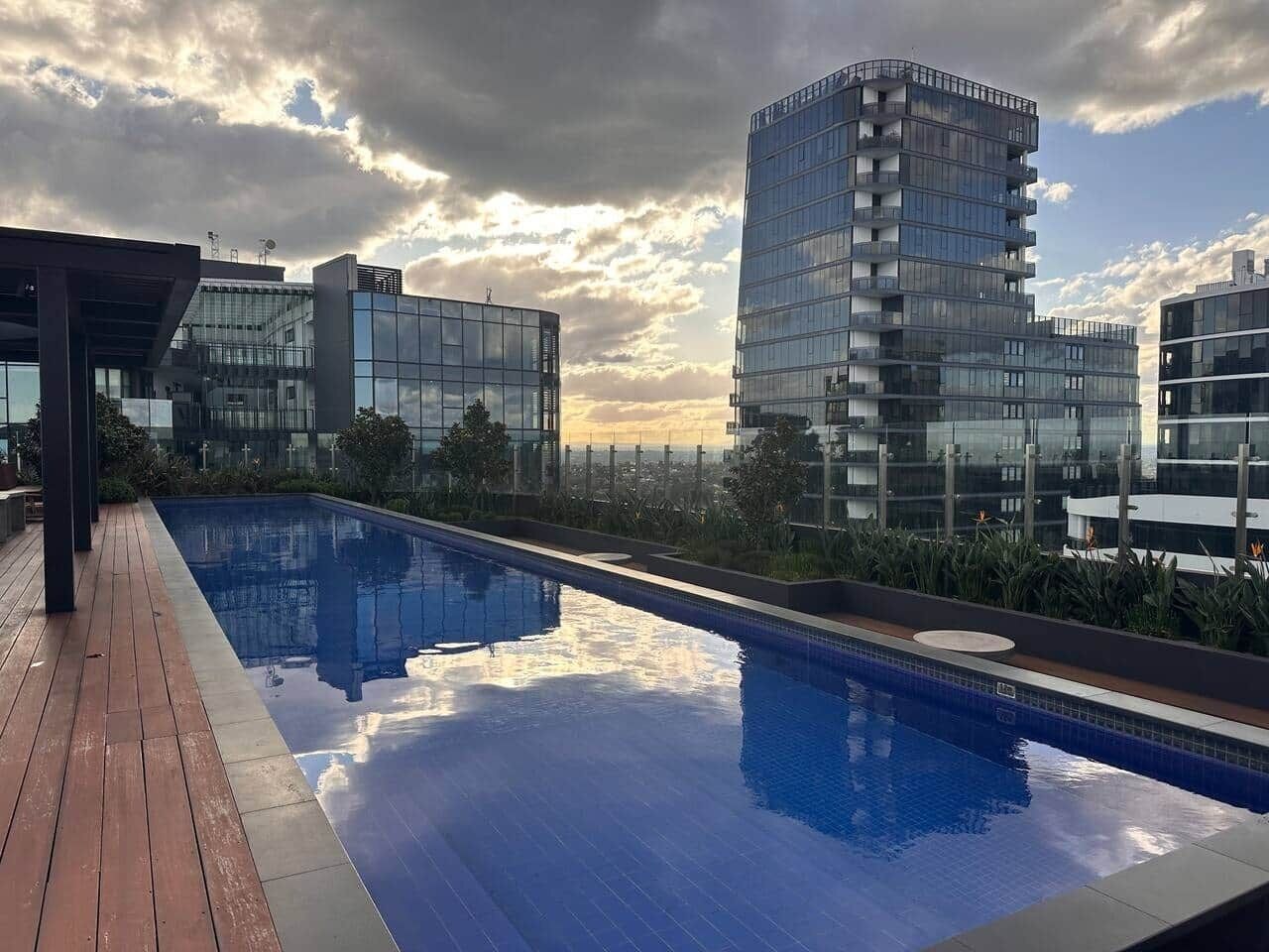A rooftop swimming pool with modern buildings in the background.
