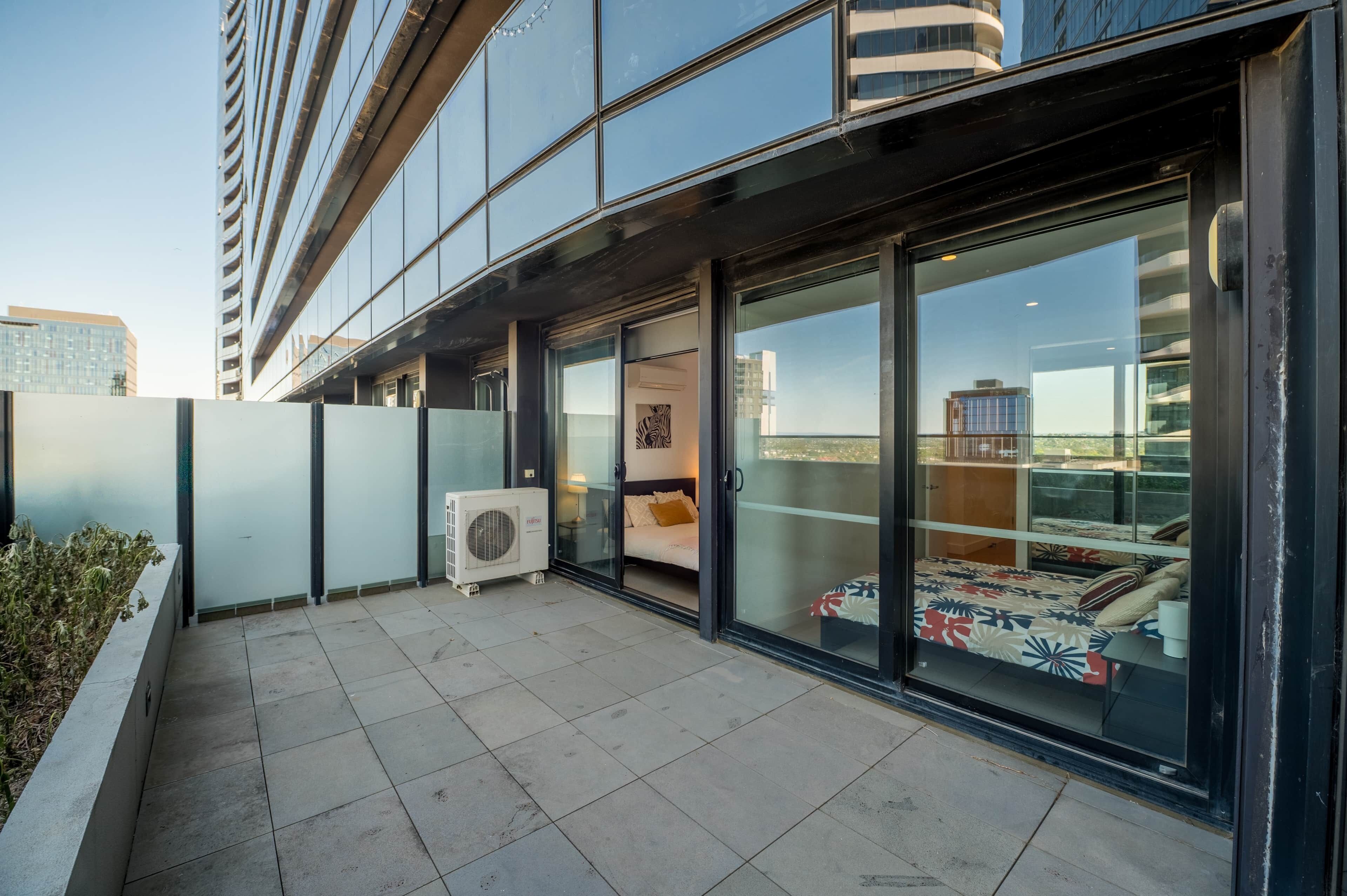 A modern building with a balcony, large windows, and an air conditioning unit.