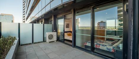 A modern building with a balcony, large windows, and an air conditioning unit.