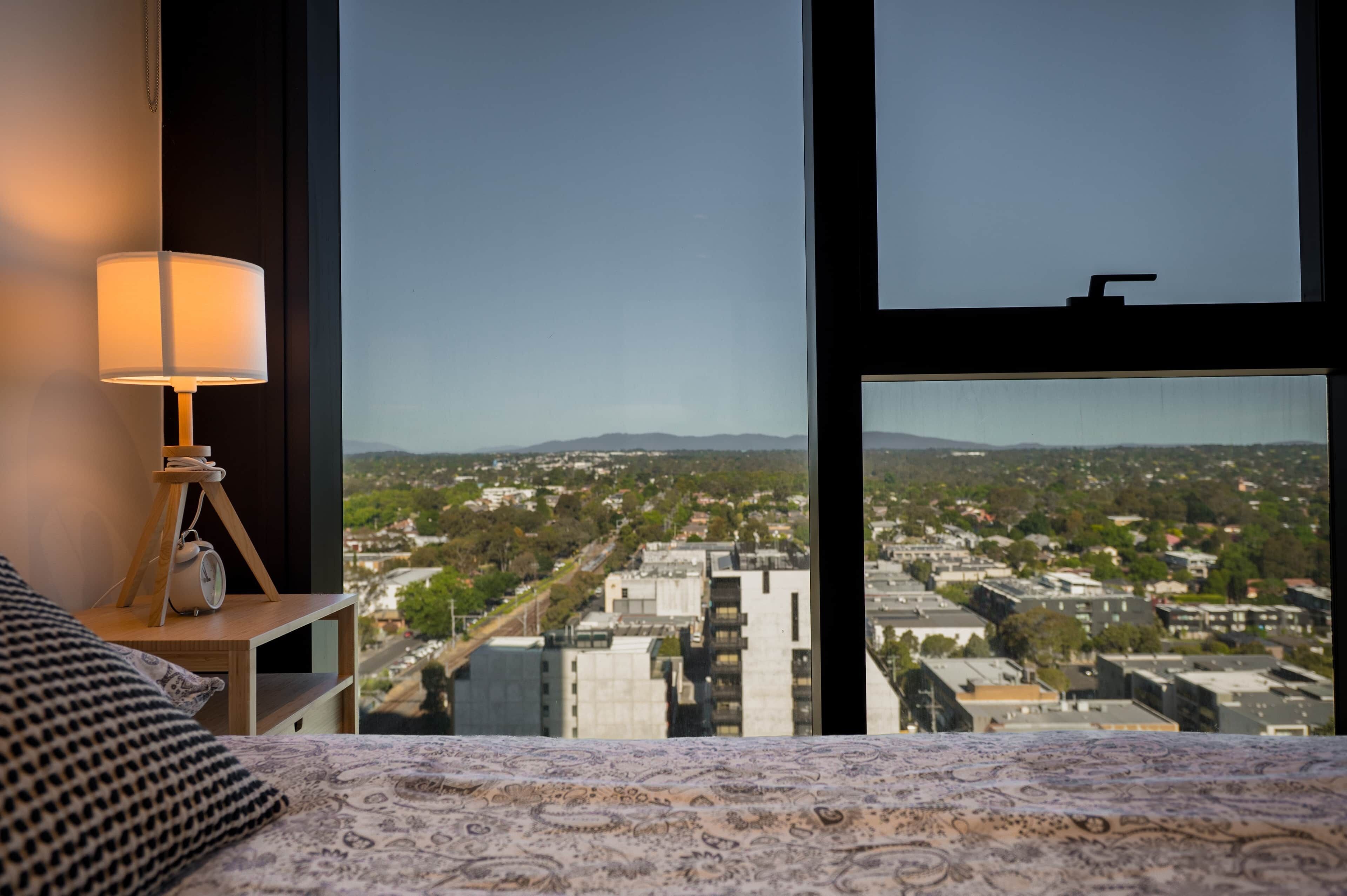 Habitación de hotel con un amplio ventanal que ofrece vistas a un paisaje urbano.