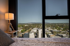 A hotel room with a large window offering a view of a cityscape. - Sky One Harmony Apartment (Box Hill)