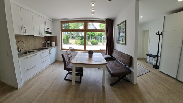 A modern kitchen with a dining area, large windows, and a view of greenery. - Rebstock Apartment in the wine-growing region of Baden-Baden. (Baden-Baden)