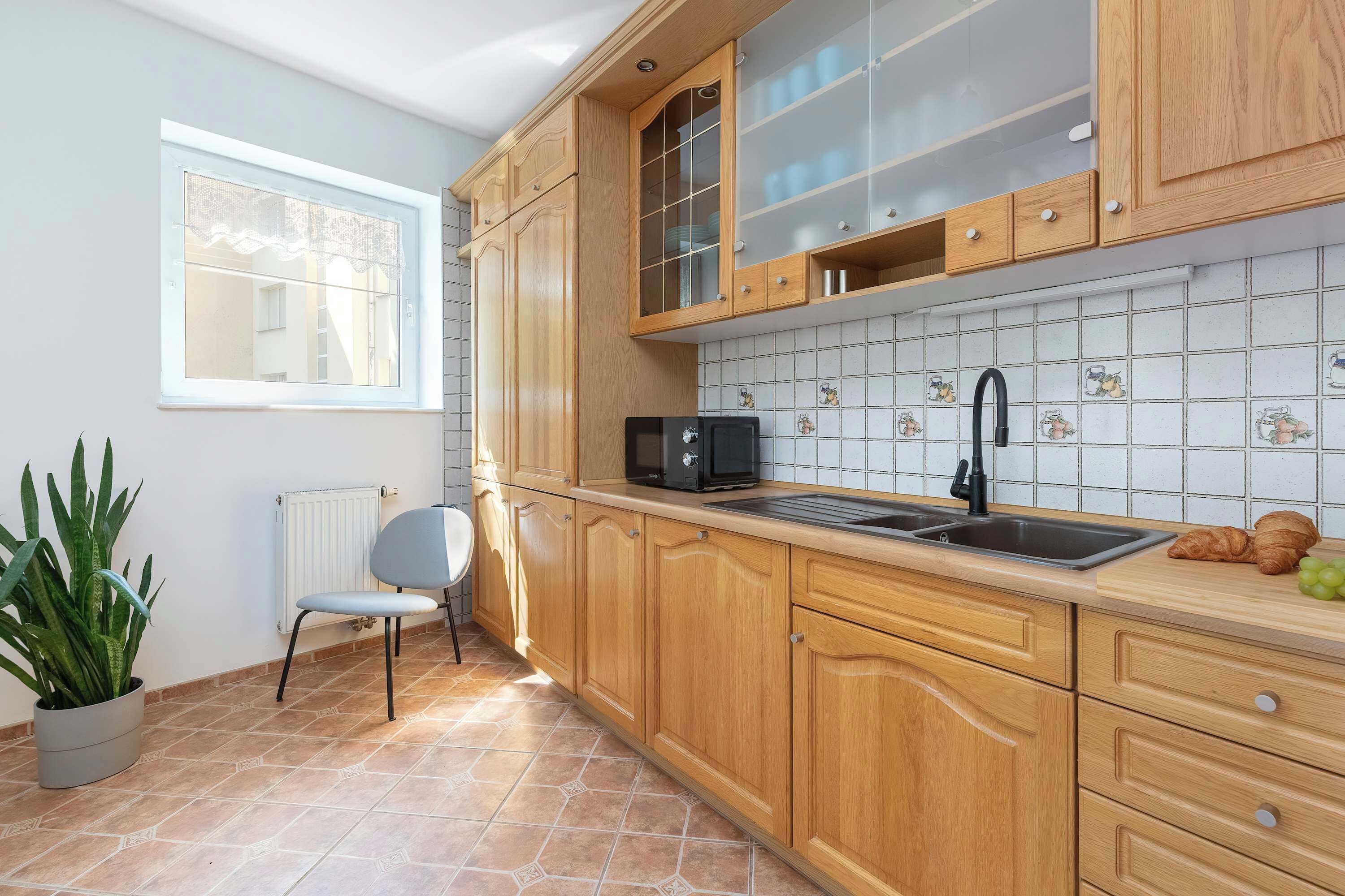 Una cocina con armarios de madera, un microondas, un lavamanos y una ventana.