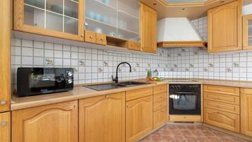 A kitchen with wooden cabinets, a microwave, a sink, and an oven.
