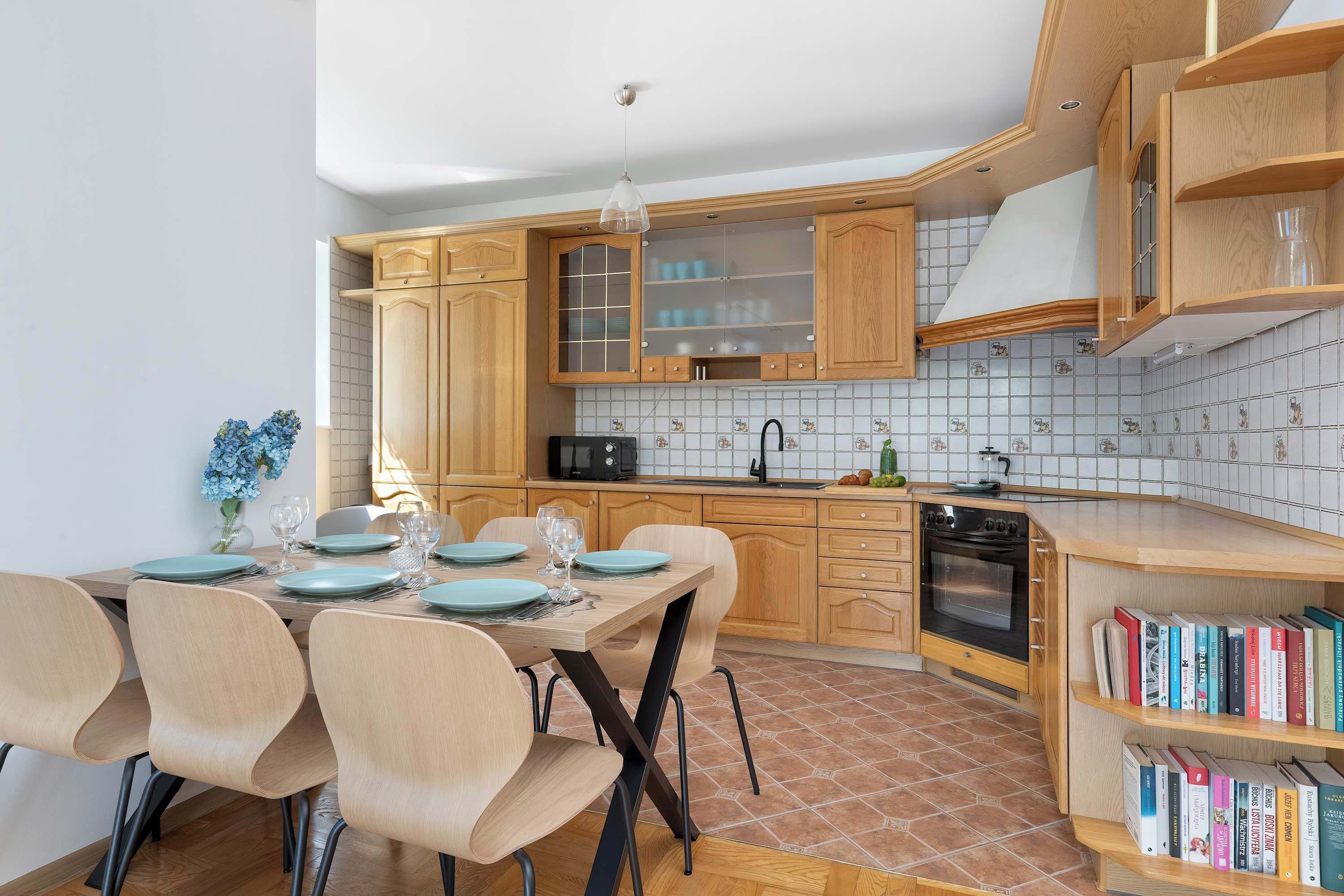 Una cocina moderna con armarios de madera, una mesa de comedor para cuatro personas y una estantería empotrada.