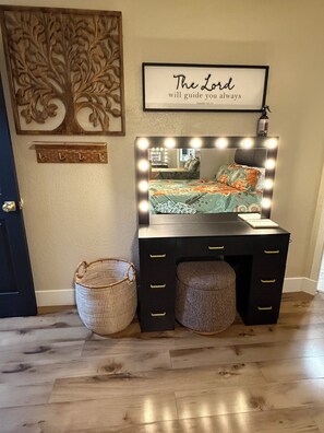Une coiffeuse avec un miroir et des lampes, ainsi qu’un lit recouvert d’une couvre-lit à motifs floraux.