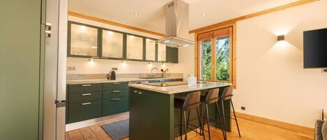 Una cocina moderna con una isla central, taburetes de bar y una ventana que ofrece vistas a zonas verdes.