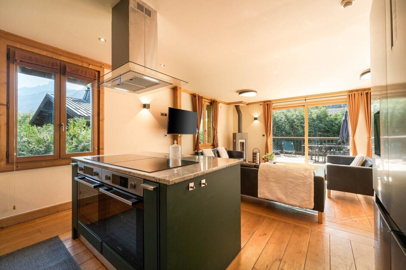 A modern kitchen with an island, built-in oven, and a large window overlooking greenery.