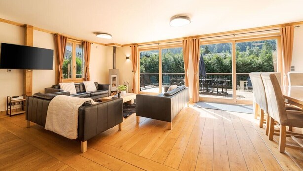 Ein geräumiges Wohnzimmer mit Kamin, Flachbildfernseher und Balkon mit Sitzgelegenheit.
