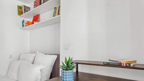 Een moderne woonkamer met een witte bank, een houten salontafel met een plant, en boekenplanken tegen de muur.