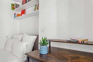 Ein modernes Wohnzimmer mit einem weißen Sofa, einem Holztisch mit Pflanze und Bücherregalen an der Wand.