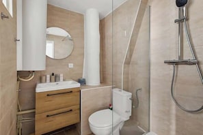 Ein modernes Badezimmer mit Duschkabine aus Glas, Toilette und Waschtisch mit Schubladen.