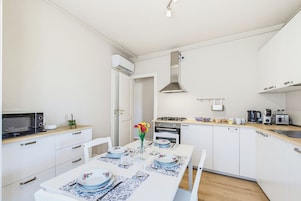 Una cocina moderna con armarios blancos, microondas, estufa y cafetera.