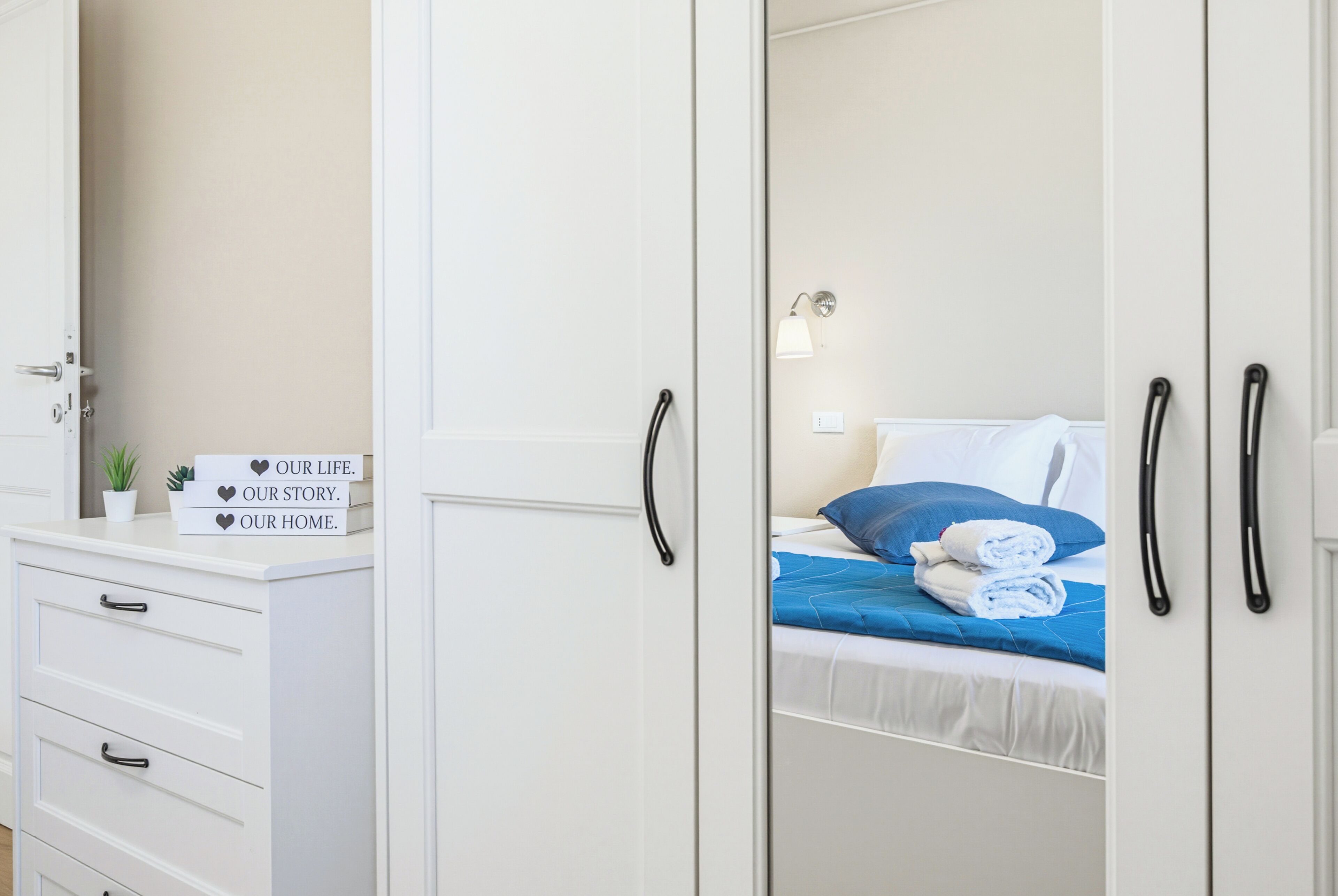 A bedroom with a bed, a nightstand, a dresser, and a mirror.