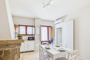 A compact kitchen with a dining area, white cabinetry, and a stone accent wall. - Il Giardino di Rosa e Gli Olivi di Rosa (Lavaiano)
