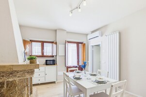 Una cocina compacta con comedor, muebles de cocina blancos y una pared de acento de piedra.