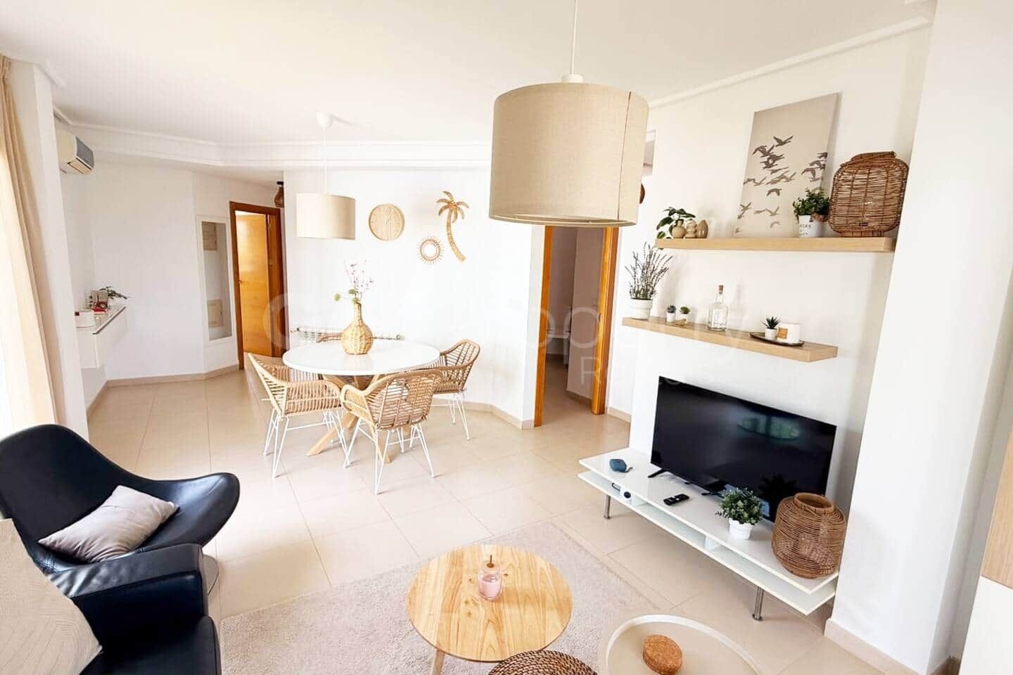 A modern living room with a TV, a dining area with a round table, and a black leather chair.
