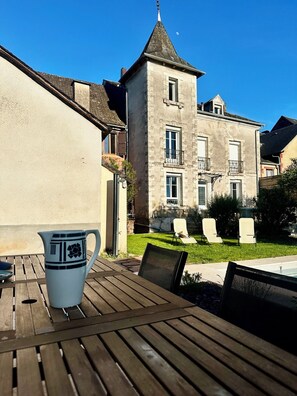 A courtyard with a wooden table, a white pitcher, and a cat.