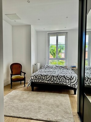 A bedroom with a bed, a chair, a window with a view, and a radiator. - Manor house + swimming pool (Meyssac)
