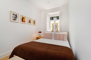 Ein Schlafzimmer mit einem Bett, einem Nachttisch, einer Lampe und drei gerahmten Bildern an der Wand.