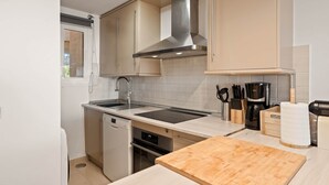 A kitchen with a dishwasher, oven, sink, and a wooden cutting board. - RDR576 - Sea Views 2 Bed Apartment in Sea&Sun Hills (Estepona)