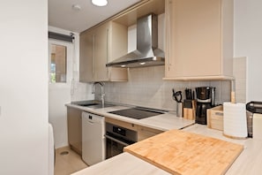 A kitchen with a dishwasher, oven, sink, and a wooden cutting board. - RDR576 - Sea Views 2 Bed Apartment in Sea&Sun Hills (Estepona)