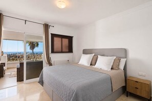 A bedroom with a bed, a nightstand, a window, and a view of the outdoors. - RDR576 - Sea Views 2 Bed Apartment in Sea&Sun Hills (Estepona)
