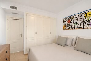 A bedroom with a bed, a wardrobe, and a wall with abstract art. - RDR576 - Sea Views 2 Bed Apartment in Sea&Sun Hills (Estepona)