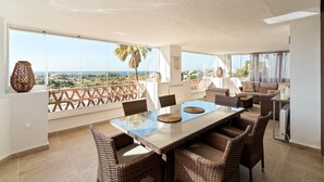 A spacious balcony with a dining area, wicker furniture, and a view of the cityscape. - RDR576 - Sea Views 2 Bed Apartment in Sea&Sun Hills (Estepona)