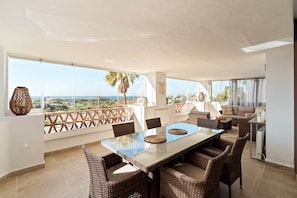A spacious balcony with a dining area, wicker furniture, and a view of the cityscape. - RDR576 - Sea Views 2 Bed Apartment in Sea&Sun Hills (Estepona)