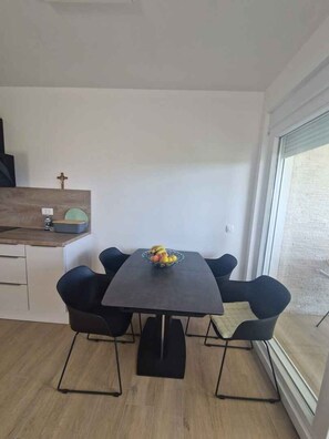 A modern kitchen with a dining table and chairs, a small countertop, and a window with a view. - Holiday apartment with garden and air conditioning (Turanj)