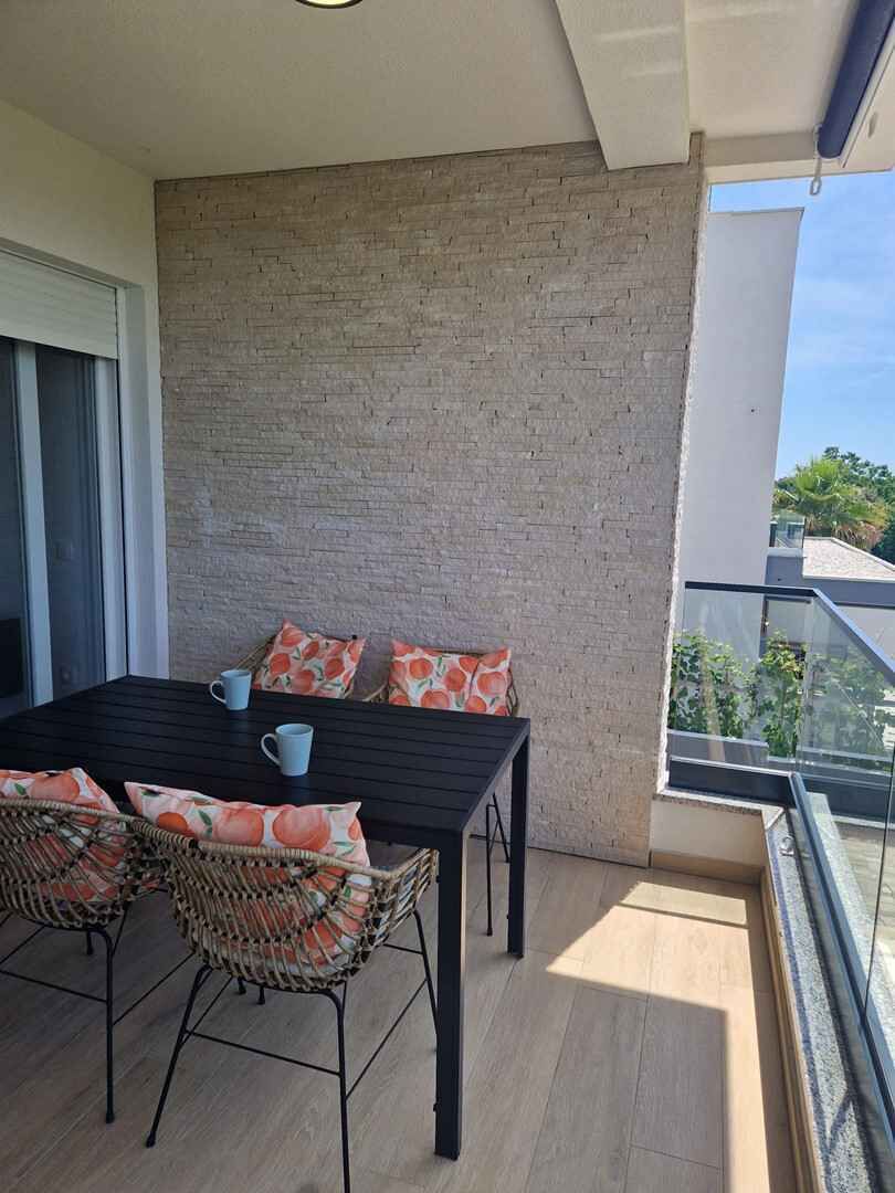 Een balkon met een tafel en stoelen, een bakstenen muur en een uitzicht op de lucht.