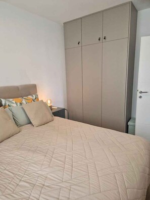 A bedroom with a bed, a wardrobe, and a nightstand with a lamp. - Holiday apartment with garden and air conditioning (Turanj)