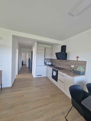 A modern kitchen with a wooden countertop, a built-in oven, and a black range hood. - Holiday apartment with garden and air conditioning (Turanj)