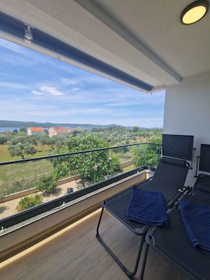 A balcony with a view of a rural landscape, including trees and buildings. - Holiday apartment with garden and air conditioning (Turanj)