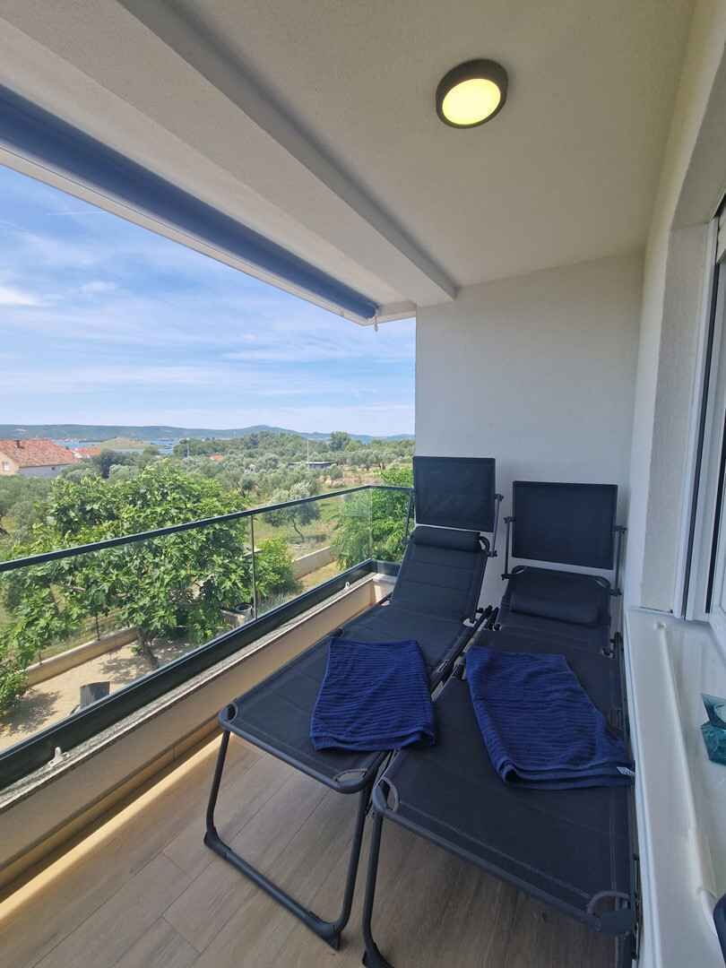 A balcony with two reclining chairs and a table, overlooking a scenic landscape.