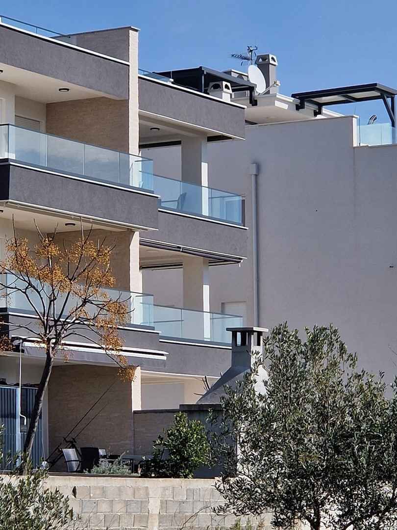 A multi-story residential building with balconies, a satellite dish, and a chimney.