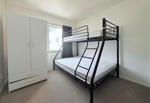 A bunk bed with a wardrobe and a window.