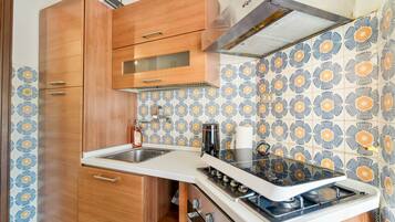 Une cuisine de taille réduite avec des meubles en bois, un plan de travail blanc et un pare-feu décoratif.