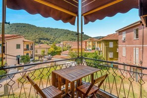 A balcony with a table and chairs, overlooking a residential area with houses and a hill in the background. - [CasettaDellePunte]Road to lerici-Air conditioning (Romito Magra)